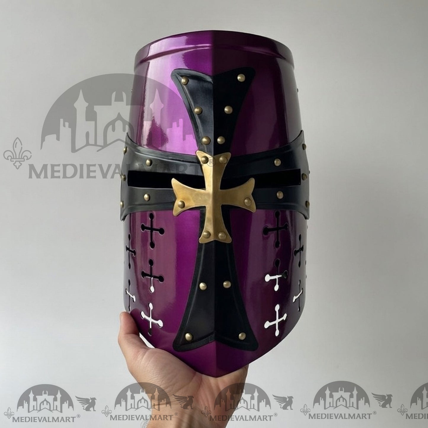 Purple and black medieval helmet with gold accents held by a hand against a gray background.
